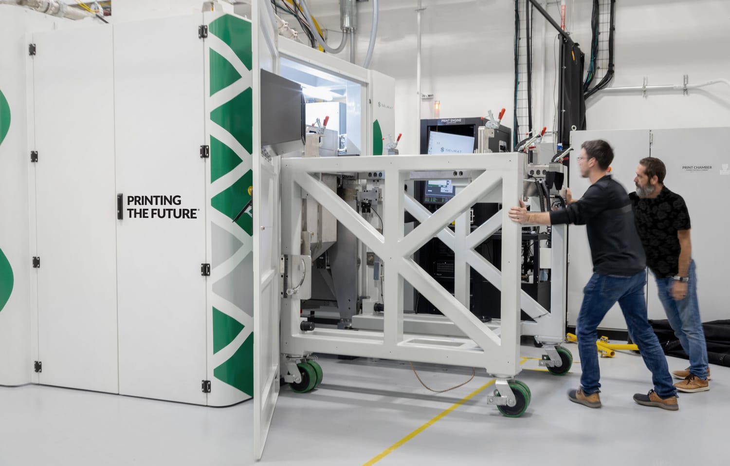 Seurat Technologies’ Alpha System metal 3D printer with its enclosure open, engineers moving a steel frame across the print depot floor